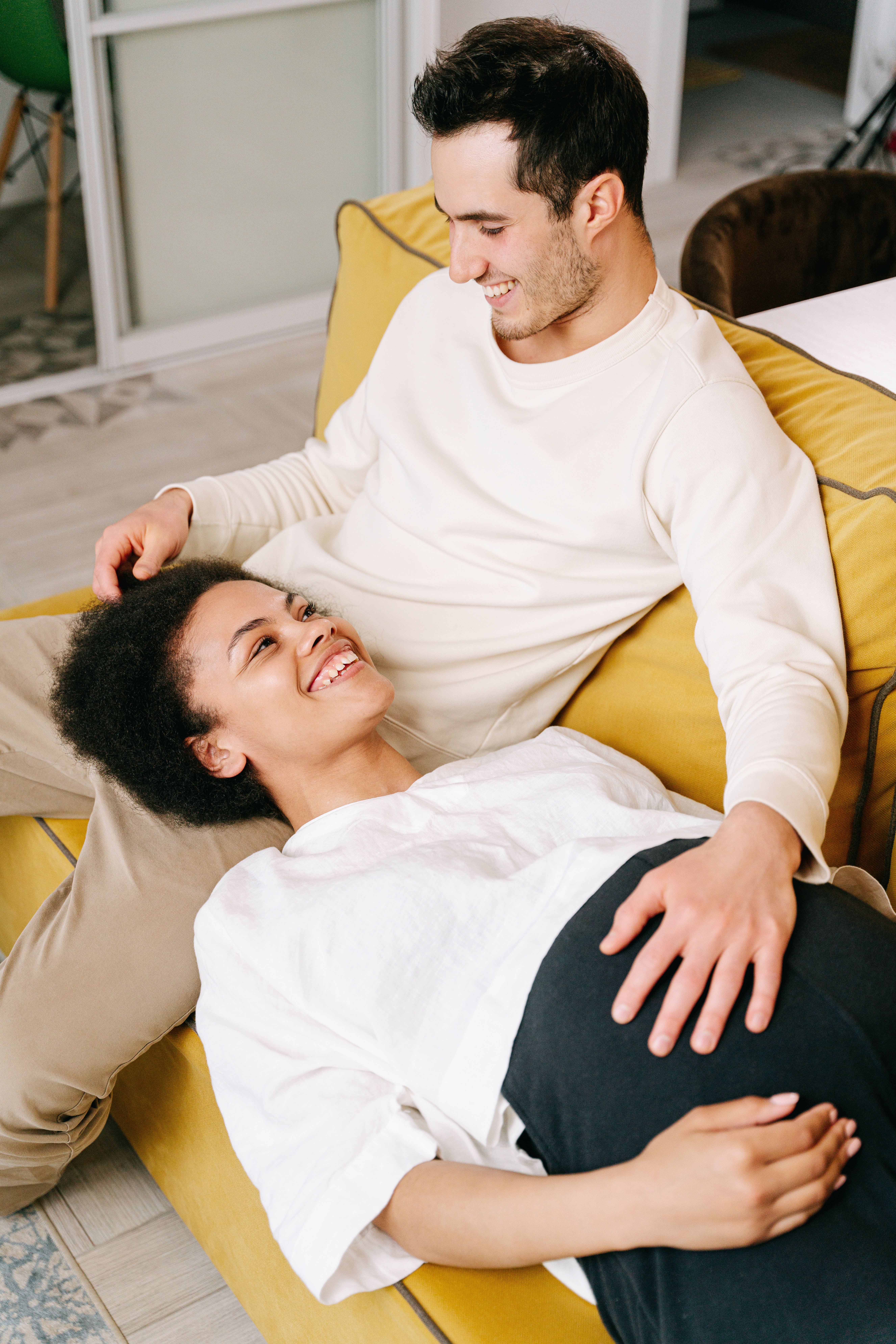 Pregnant person lying their head in a partner's lap on couch.